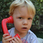 Young boy talking on a toy phone.