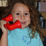 Smiling girl talking on a toy phone.