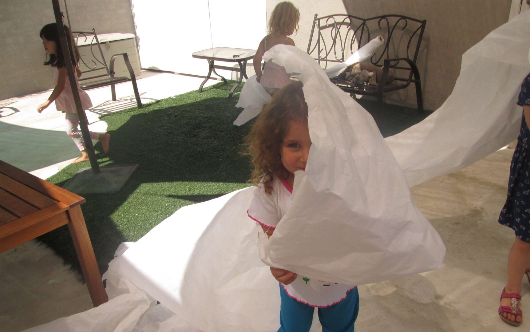 Girl playing with white paper outside.