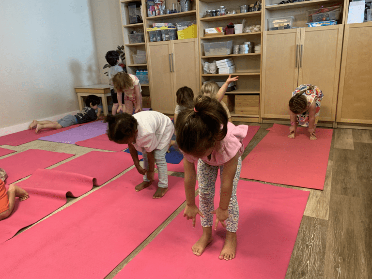 Children practicing yoga on pink mats.